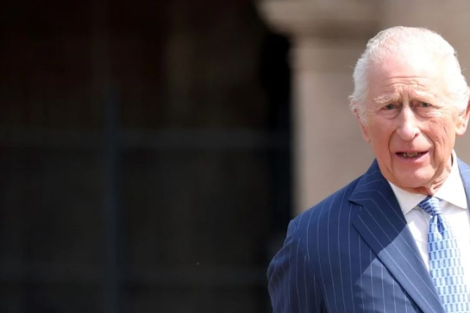 HRH King Charles looking directly at the camera stood against a blurred background